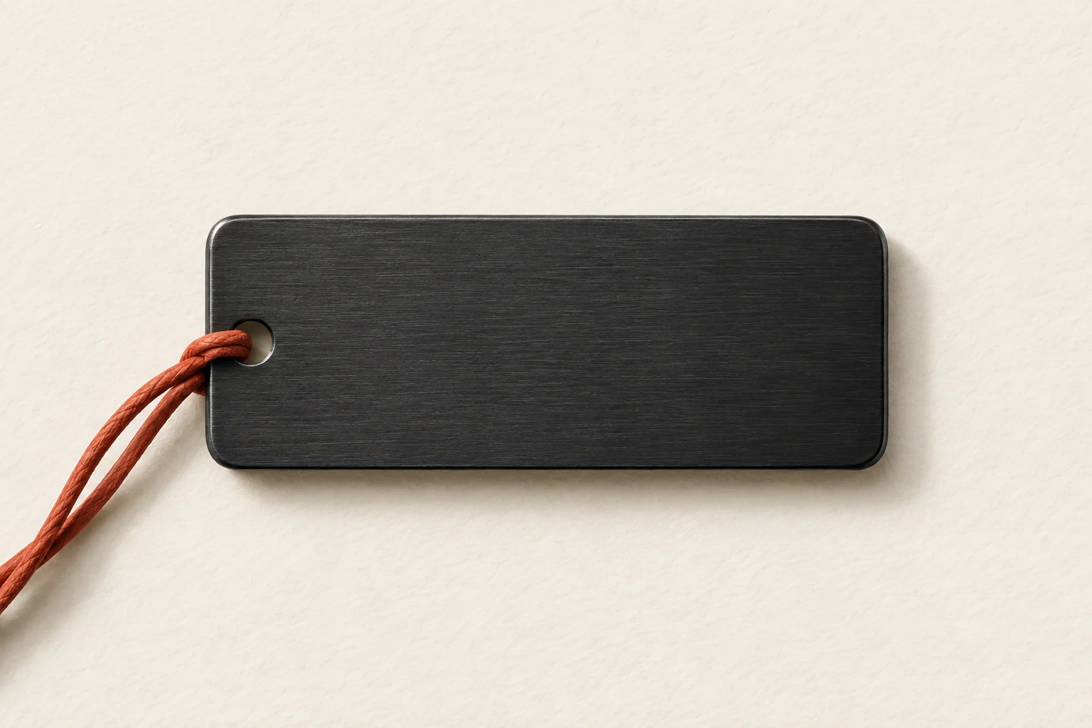Illustrative blank charcoal keepsake tag on ivory paper with a terracotta cord